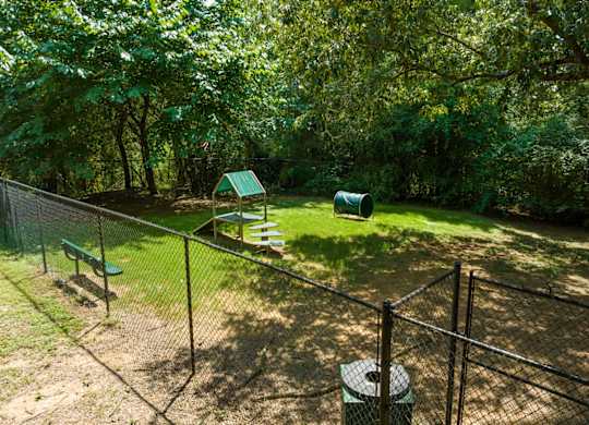 The pet bark park with trees and obstacles and a bench at Summerchase at Riverchase in Hoover, Alabama.