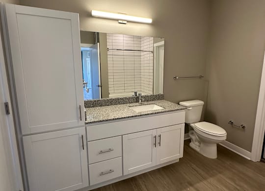 Modern bathroom with white cabinets and stone countertops at The Fitzroy Apartments in Birmingham, AL
