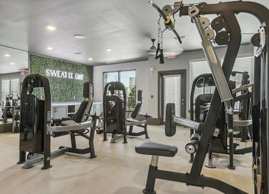 a gym with weights and cardio equipment and a sign on the wall