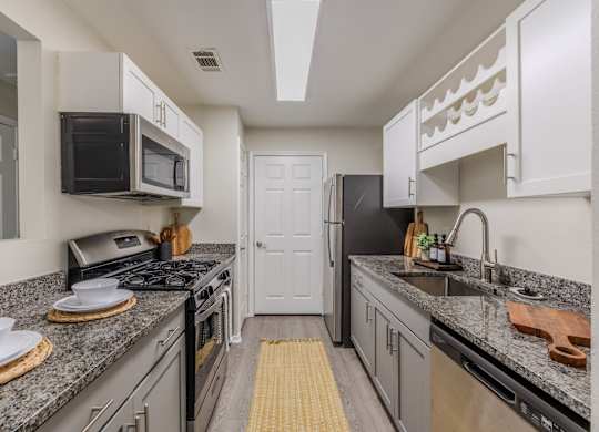 A kitchen with a black stove top oven and a black microwave above it at Grande View Apartments in Biloxi, MS