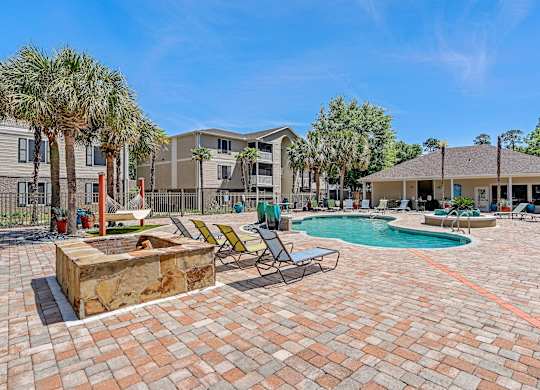 A sunny day at a residential complex with a pool and palm trees.