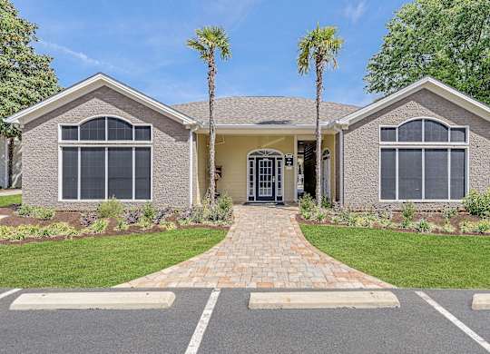A house with a driveway and a palm tree in front.
