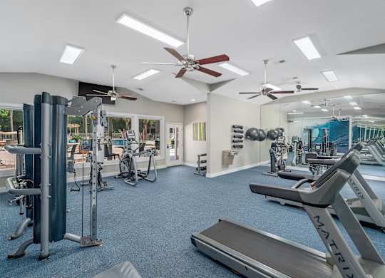 A gym with a variety of equipment including treadmills, weights, and exercise machines.