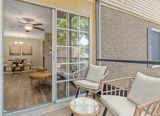 A patio with a table, chairs, and a ceiling fan.