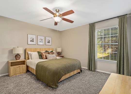 A bedroom with a bed, nightstands, and a ceiling fan.