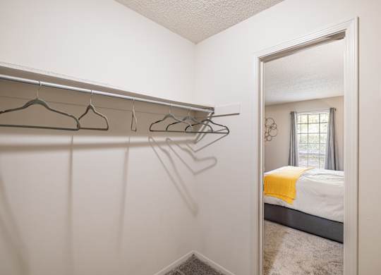 A white bedroom with a bed, a window, and a mirror.