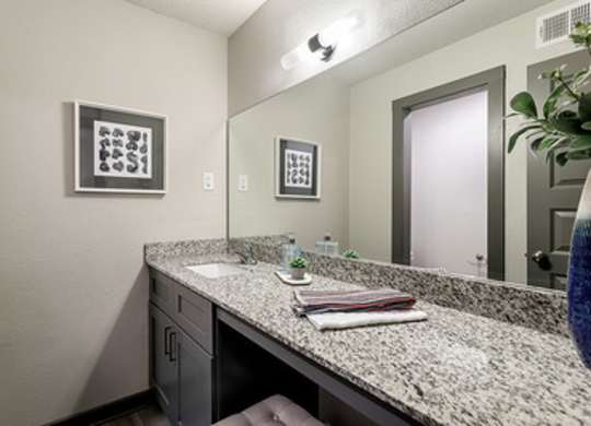 A bathroom with a granite countertops and oversized vanity at Avia Apartments in Vestavia Hills, AL