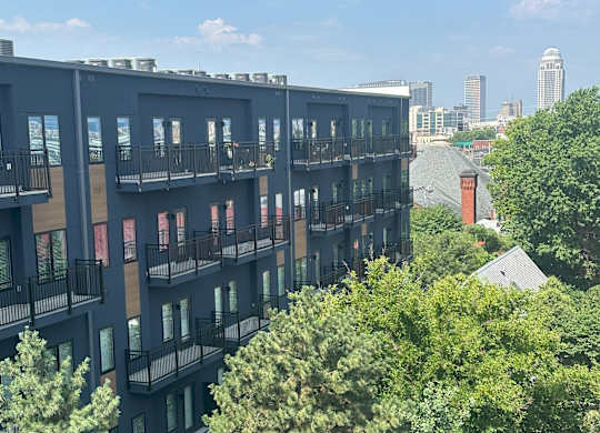 an aerial view of a building with trees in the foreground and the city in the background
