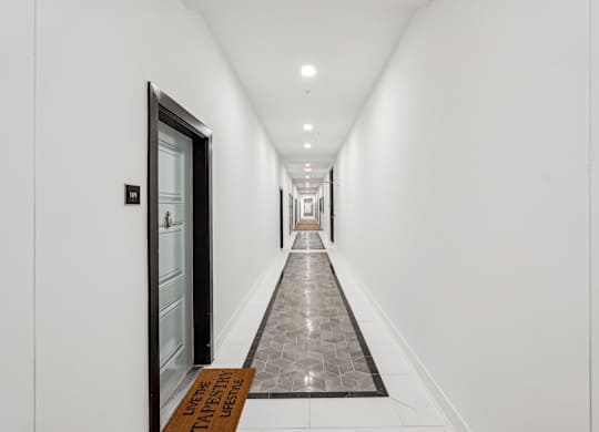 A long interior hallway with a tiled floors at Tapestry University Park apartments in Sarasota, FL