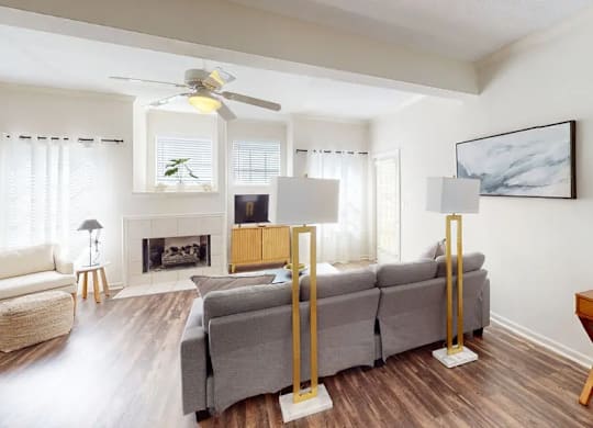 A living room with a grey couch, a fireplace, and a painting on the wall.
