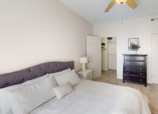 A bedroom with a bed, dresser, and ceiling fan.