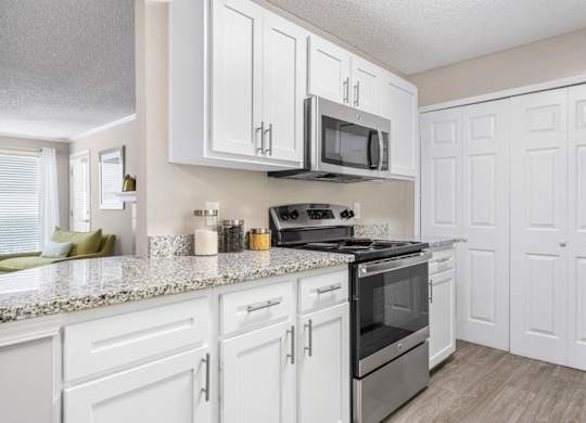 A kitchen with white cabinets, granite counters and the laundry closet at Summerchase at Riverchase in Hoover, Alabama