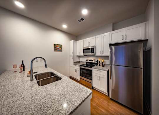 A kitchen with a granite countertop and stainless steel appliances at Wesley Place Apartments in Indianapolis, IN.