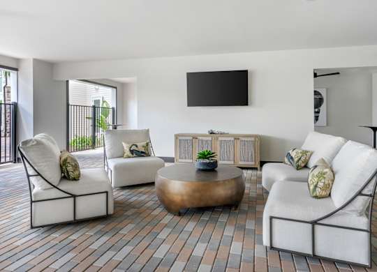 A living room with white furniture and a flat screen TV mounted on the wall.