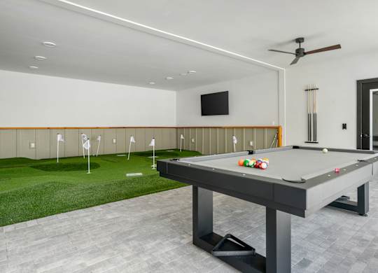A pool table in a room with a television and a fan.