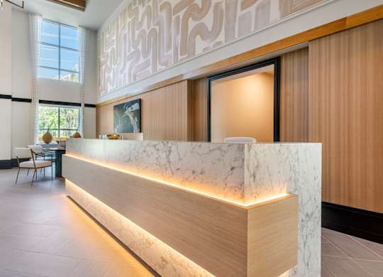 A reception area with a marble counter and wooden lighting.