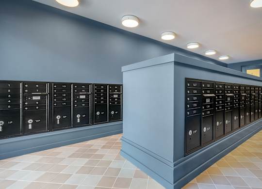 A row of black safe deposit boxes are lined up against a wall.