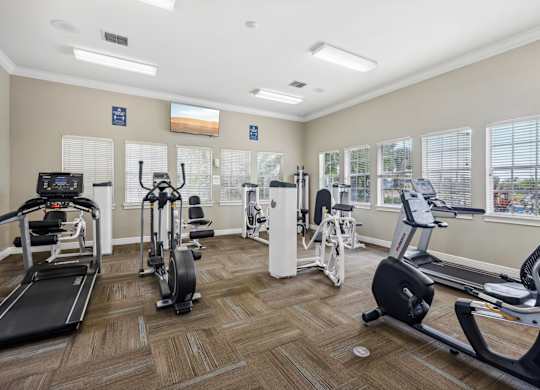 A gym with treadmills, elliptical machines, and other exercise equipment.
