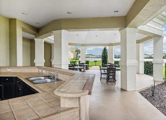 a large porch with a sink and a patio with tables and chairs
