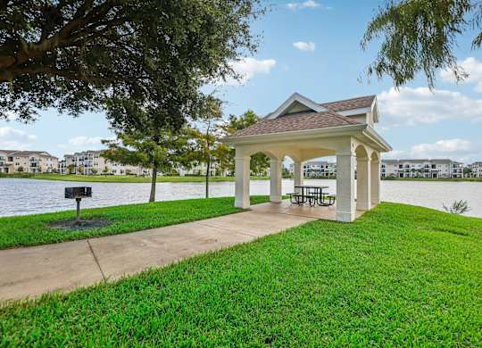 a gazebo with a picnic table on the grass next to the water