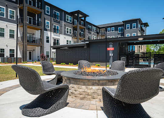 A fire pit sits in the middle of a patio surrounded by chairs.