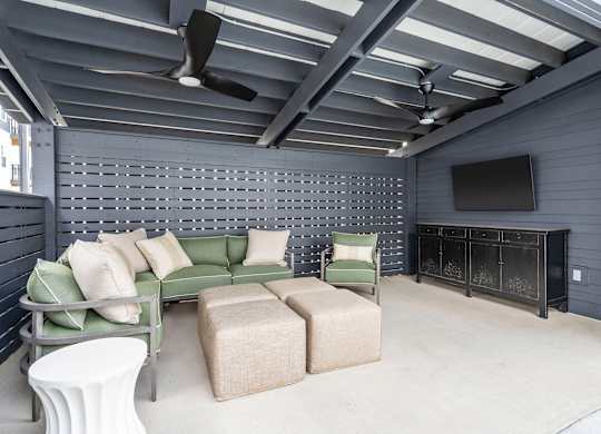 A living room with a green couch, a white table, and a television.