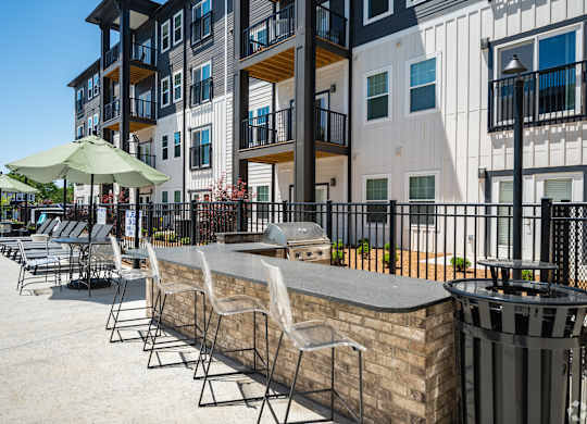 A patio with chairs and a bar area in front of a building.