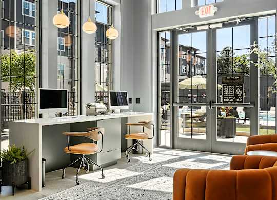 A modern office space with orange chairs and a glass door entrance.