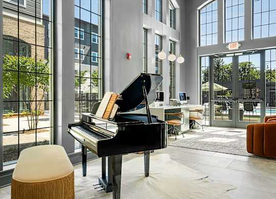 A grand piano sits in a room with a lot of windows.