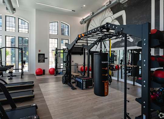 A gym with a variety of equipment including treadmills, weights, and a punching bag.