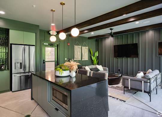A modern kitchen with a dark countertop and green cabinets.