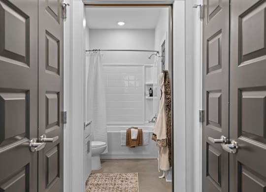 A bathroom with a toilet, a shower, and a towel hanging on the wall.