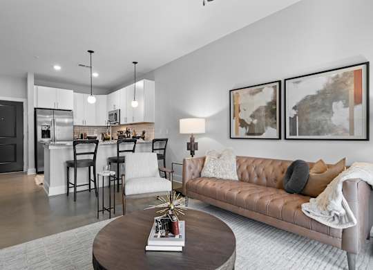 A modern living room with a brown leather couch and a coffee table in the center.