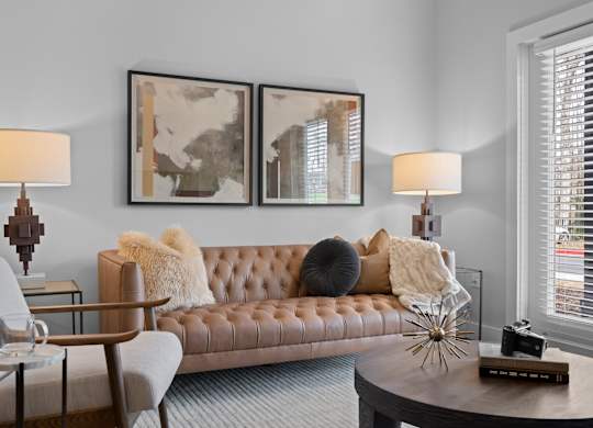 A brown leather couch with a grey cushion and a white throw on it.