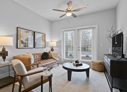 A living room with a brown leather couch, a wooden chair, a coffee table, and a flat screen TV.