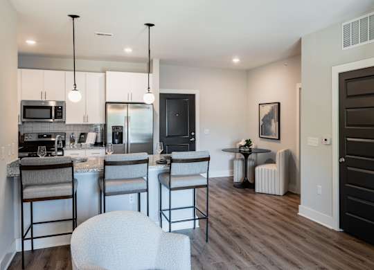 A modern kitchen with white chairs and a black door.