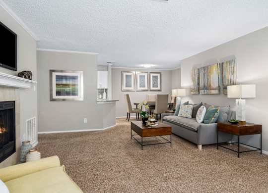 A carpeted open-concept living room with a fireplace at Summerchase at Riverchase in Hoover, Alabama.