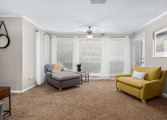 A living room with large windows , carpet and a ceiling fan at Summerchase at Riverchase in Hoover, Alabama.