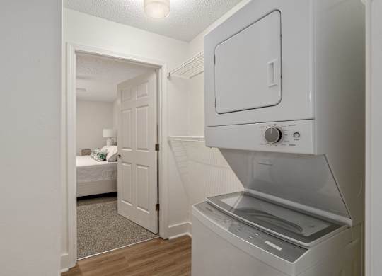 A white oven with a door open is in a room with a bed in the background.