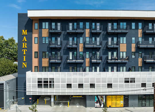 the front of a hotel building with balconies and a large white and black building