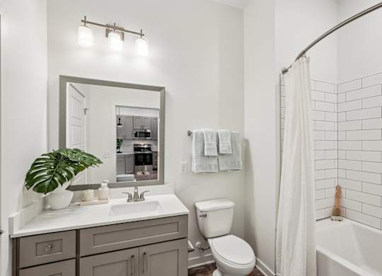 A bathroom with a white sink, toilet, and bathtub with subway tiled surround at Tapestry University Park apartments in Sarasota, FL.