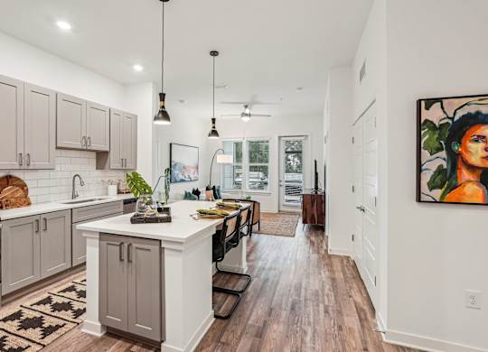 A kitchen with a white island and wooden floors at Tapestry University Park apartments in Sarasota, FL