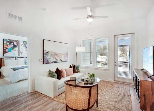 Open living room with wood floors, ceiling fan, and patio access.
