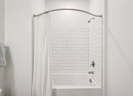 A white bathroom with white tub and shower combo at Tapestry University Park apartments in Sarasota, FL