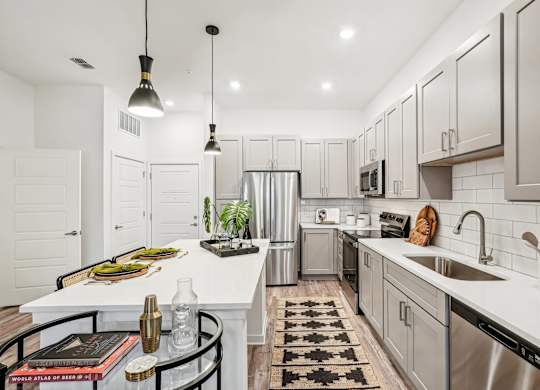 A modern kitchen with a white island and stainless steel appliances at Tapestry University Park apartments in Sarasota, FL