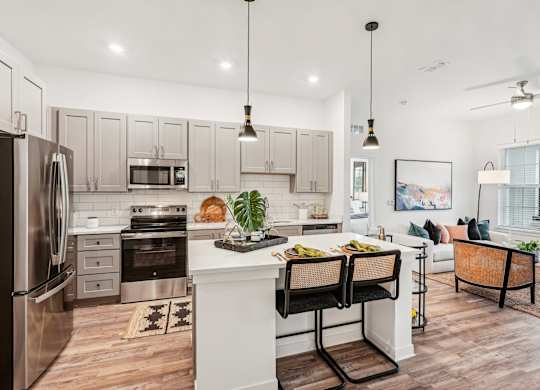 A modern kitchen with a white island and stainless steel appliances at Tapestry University Park Apartments in Sarasota, FL