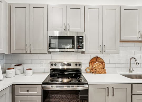 A kitchen with a stove, microwave, and custom cabinetry at Tapestry University Park apartments in Sarasota, FL