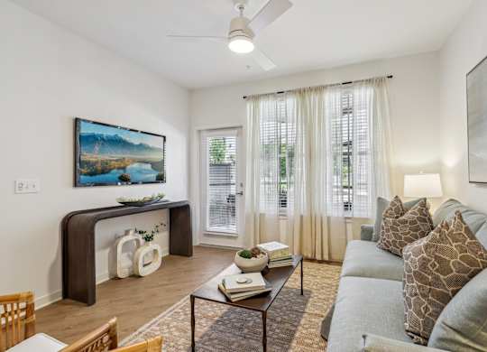 A living room with a grey couch and a painting on the wall.