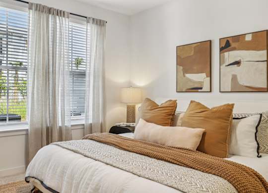 A bedroom with a large bed and two abstract paintings on the wall.