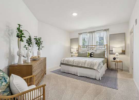 A bedroom with a bed, nightstand, and a plant.